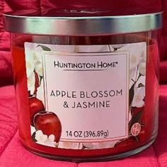 an apple blossom and jasmine candle in a glass jar on a pink blanket