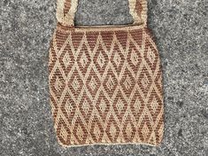 a brown and white knitted bag sitting on top of a cement floor next to a sidewalk