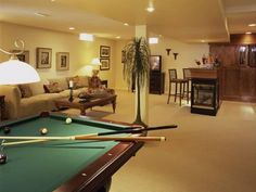 a living room with pool table, couches and bar in it's center