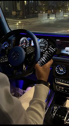 a man is driving his mercedes car in the city at night, with blue lights