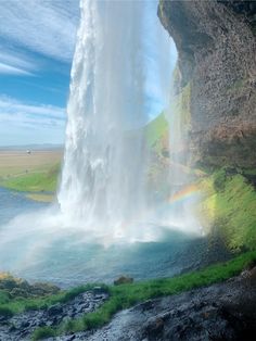 a large waterfall with a rainbow in the middle and water falling off it's side