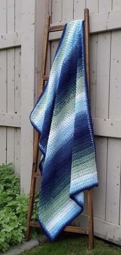 a blue and green blanket sitting on top of a wooden ladder