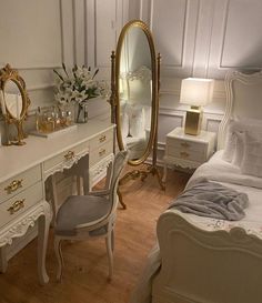 a bedroom with white furniture and gold accents on the dressers, mirror and dressing table