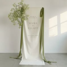 a white chair with a green ribbon tied around it and a flower in the back