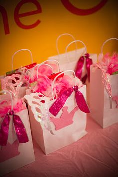 small pink and white bags with bows on them sitting on a table next to a sign