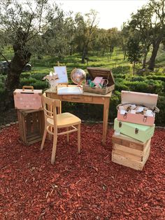 three wooden boxes sitting on top of a pile of red mulch next to a table and chair