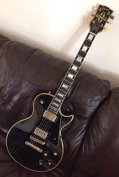 a black guitar sitting on top of a leather couch