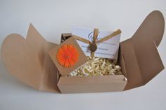 an open cardboard box filled with white rice and a orange gerberia flower in it