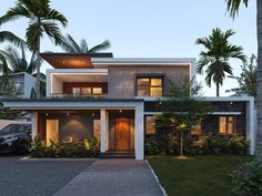 a modern house with palm trees in the front yard and driveway leading up to it