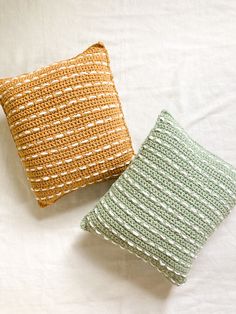 two crocheted pillows sitting next to each other