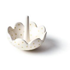 a white and gold polka dot bowl on a white surface with a spoon in it