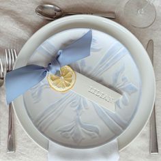 a white plate topped with a slice of lemon next to silverware and utensils