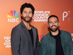 two men standing next to each other in front of a red carpet with people's choice awards written on it