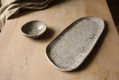 two white dishes sitting on top of a wooden table