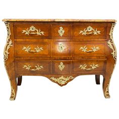 an ornately decorated wooden dresser with gold paint on it's drawers and handles