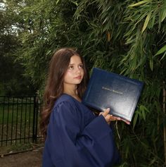 a young woman in graduation gown holding up a book with the word, congratulations written on it