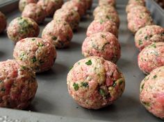 raw meatballs are lined up on a baking sheet and ready to go into the oven