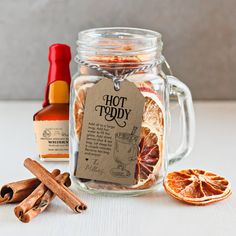 an orange slice, cinnamon and spices sit in a glass jar with a label on it