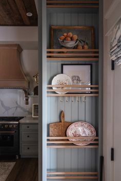 the shelves in this kitchen have plates and bowls on them, along with other items