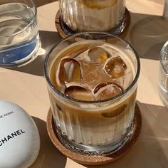 an iced drink with ice sits on a table next to two glasses and a ball