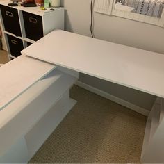 a white desk sitting on top of a carpeted floor next to a dresser and drawers