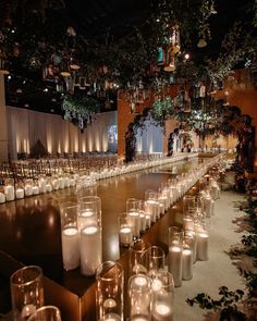 rows of lit candles are lined up on the floor in front of an audience at a wedding