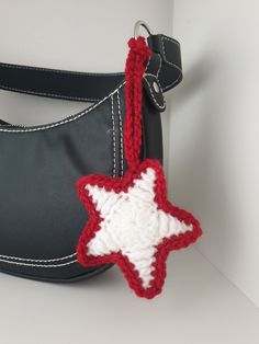 a crocheted red and white star ornament hanging from a black purse