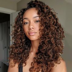 a woman with long curly hair is looking at the camera while wearing a bra top