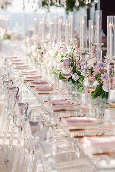 a long table is set up with clear chairs and pink napkins on the tables