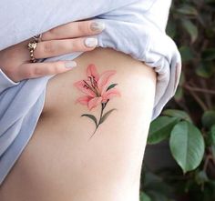 a woman's thigh with a pink flower tattoo on her left side ribcage