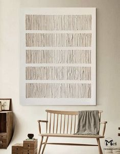 a wooden bench sitting in front of a white wall with a painting hanging above it