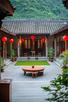 an outdoor courtyard with tables and lanterns in the middle, surrounded by greenery on both sides