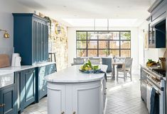 a kitchen with blue cabinets and white counter tops, an island in the middle has fruit on it