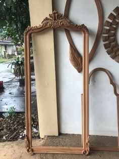 an old mirror sitting on the ground next to a wall with two mirrors hanging from it's sides