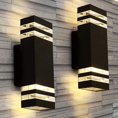 two lights are on the side of a wall next to a brick wall with white and black stripes