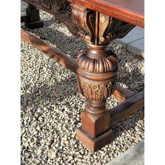 an ornately carved wooden table sitting on gravel