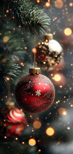 a red ornament hanging from a christmas tree with boket lights in the background