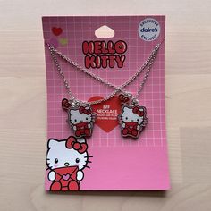 two hello kitty necklaces are on display in front of a pink card with the words hello kitty