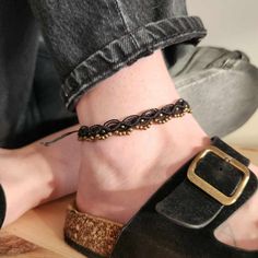 a close up of a person's foot wearing sandals and a chain ankle bracelet