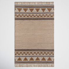 a brown and white rug with fringes on the bottom, in front of a wall