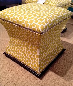 a yellow ottoman sitting on top of a carpeted floor