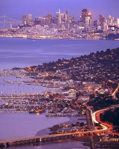 an aerial view of a city at night with the bay bridge in the foreground