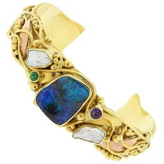 This modern designed cuff bracelet features a luscious boulder opal in the center with great play of color. It is accented with 2 pieces of mother of pearl, amethyst and tsavorite. Set in 22K yellow gold with 18K rose gold accents. The gold bead filigree and gold lines give this piece movement and flair. Fits wrists up to 5.25 inches Cuff Width: 0.75 inches Abalone Jewelry, Gold Cuff Bracelet, Antique Bracelets, Wide Cuff Bracelets, Gold Cocktail Ring, Shell Ring, Gold Bracelet Cuff, Gold Cuffs, Jewelry Rings Diamond