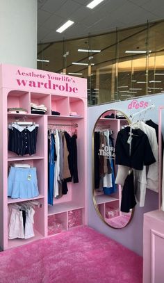 a pink room with clothes and mirrors on display