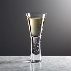 a glass filled with liquid sitting on top of a table next to a gray wall