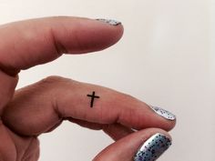 a woman's hand with a tiny cross tattoo on it, and the other half of her finger