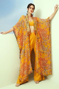 Yellow organza longline kaftan with sequins hand embroidered borders and floral and paisley print. Comes with dobby georgette bell-bottom pant and a padded bustier.
Components: 3
Pattern: Printed, Hand embroidered
Type Of Work: Floral, Paisley, Sequins
Neckline: Sweetheart
Sleeve Type: Kaftan: Flared Sleeves, Bustier: Sleeveless
Fabric: Dobby georgette, Kaftan: Organza
Color: Yellow
Other Details: 
Tasseled detailing on kaftan
Occasion: Sangeet - Aza Fashions Kaftan And Pants, Organza Kaftan, Kaftan For Women, Printed Organza, Kaftan Designs, Long Kaftan, Sharara Set, Fashion Design Sketches, Bell Bottom Pants