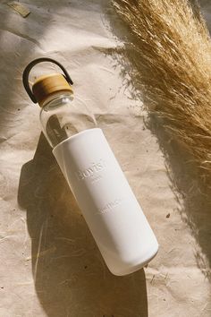 an empty glass bottle sitting on top of a piece of paper next to a dry grass