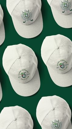 six white caps with green logos on them are lined up against a dark green background