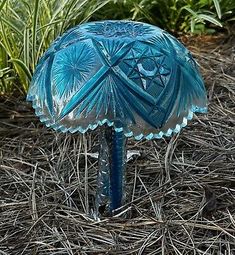 a blue glass umbrella sitting on top of dry grass